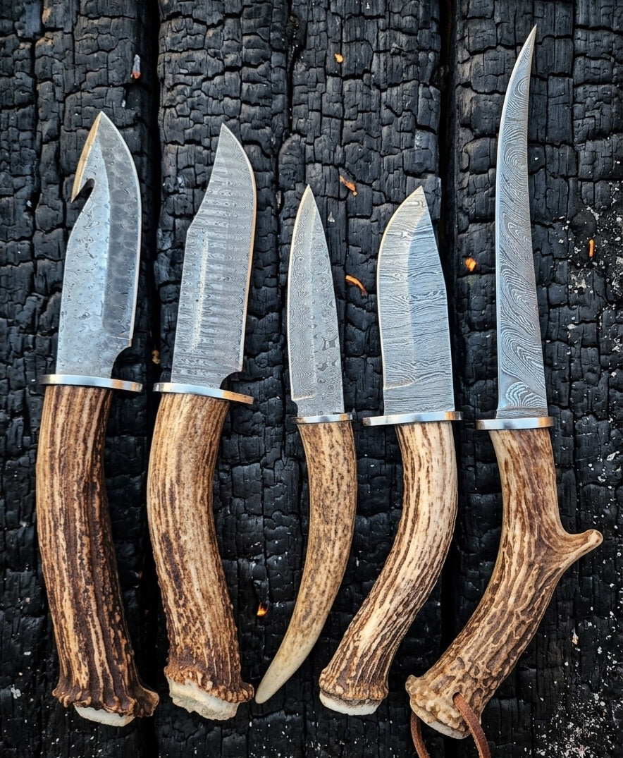 Five antler handled damascus knives on charred wood