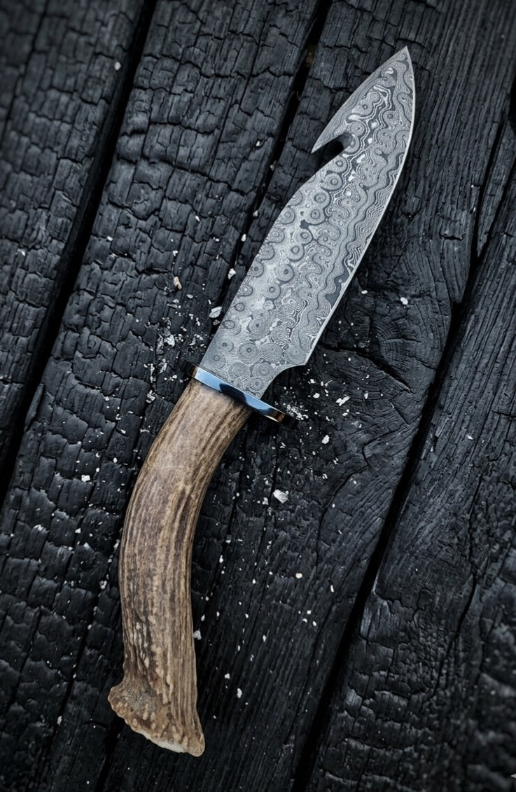 Antler handle damascus knife on charred wood